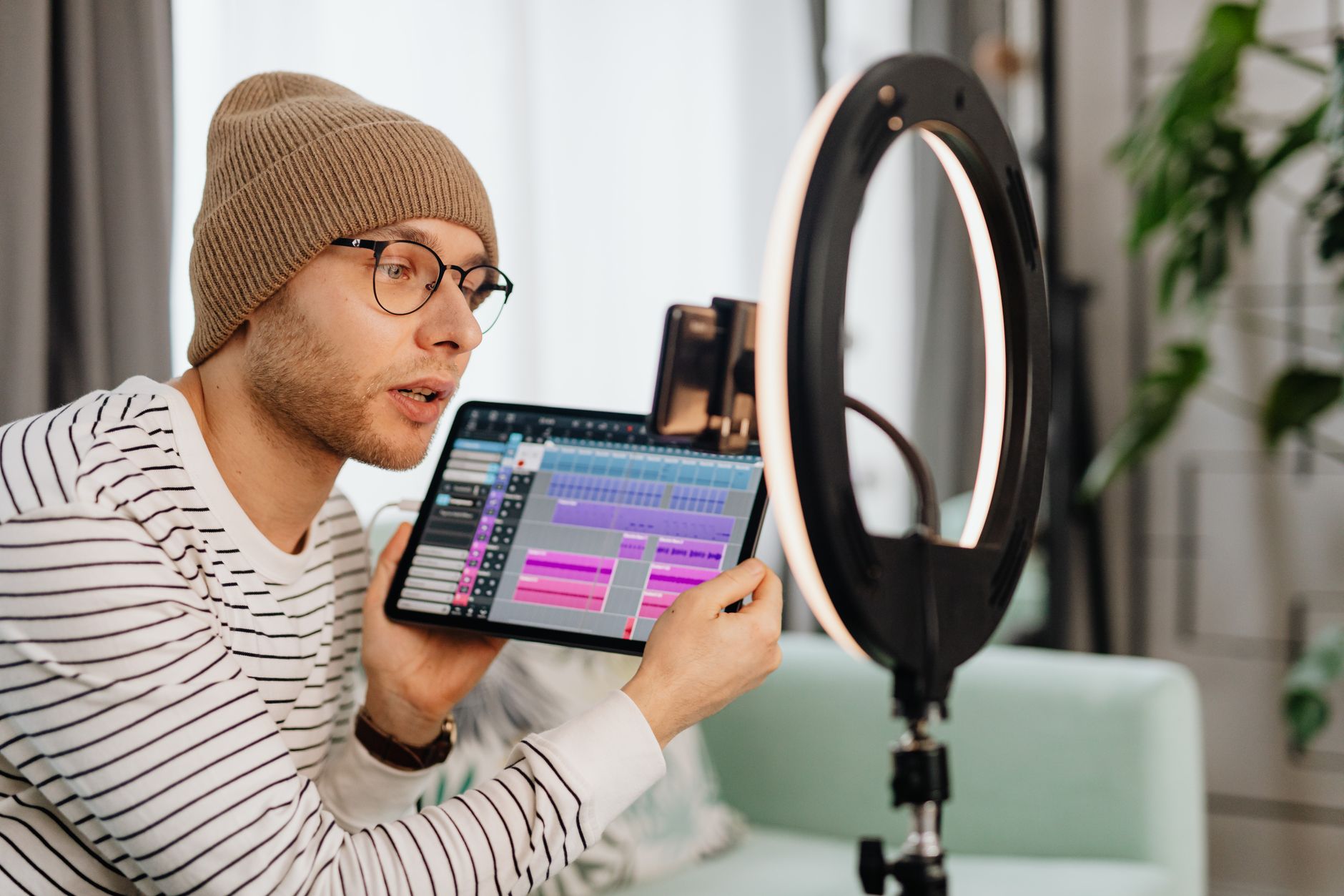 Man in a home office checks a digital product sales dashboard on a tablet with charts.