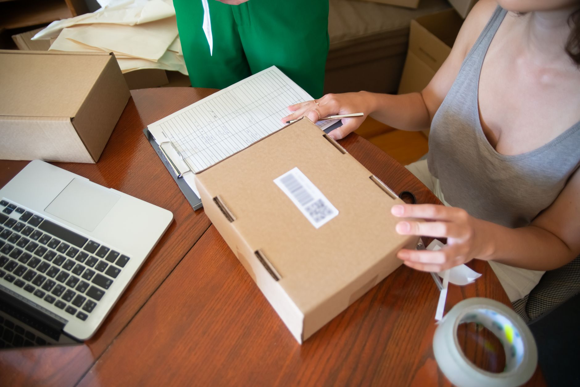 Person packing cardboard shipping boxes with labels in a home office