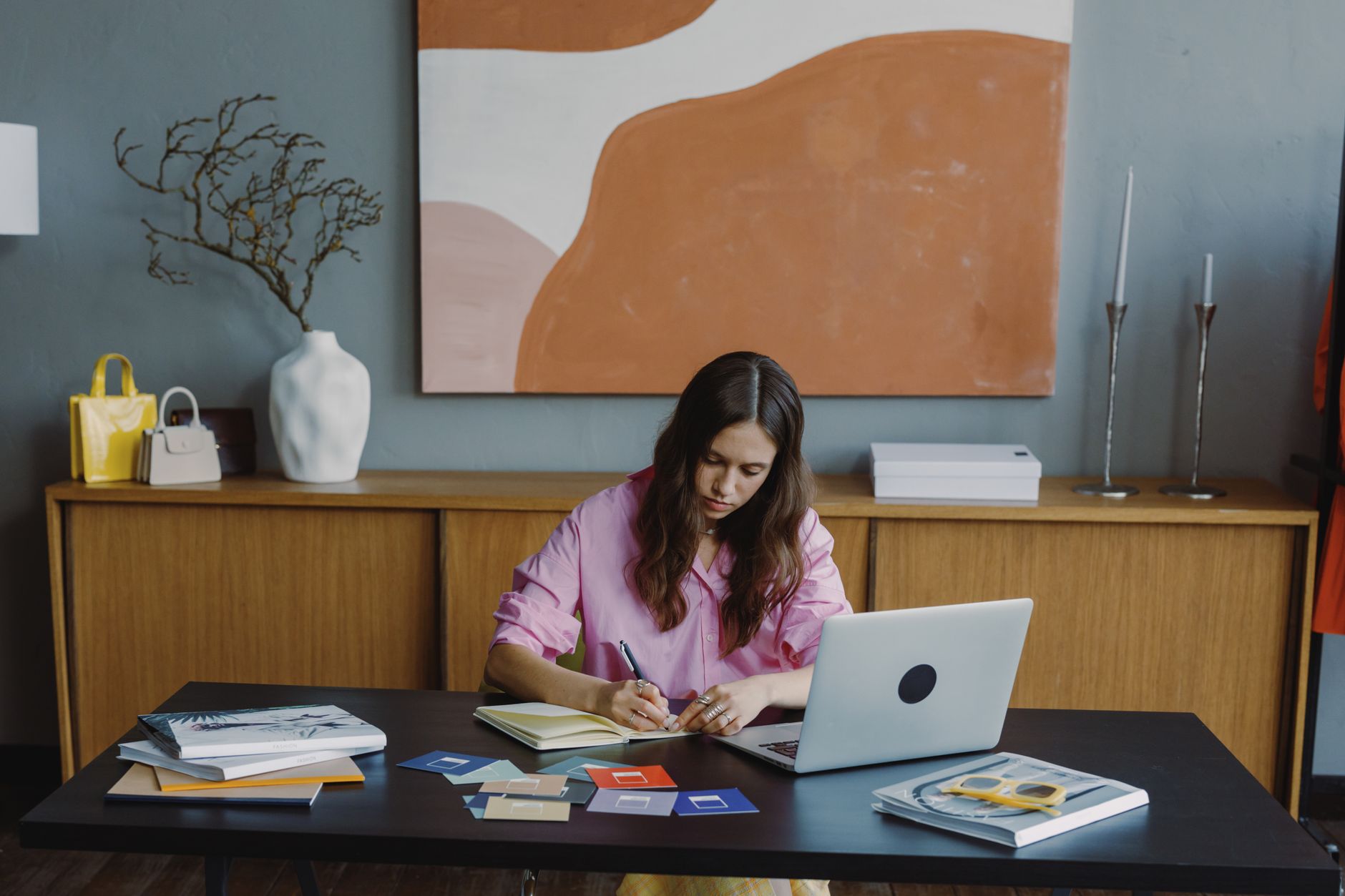 Woman at desk designing printable planner pages on a laptop with colorful swatches