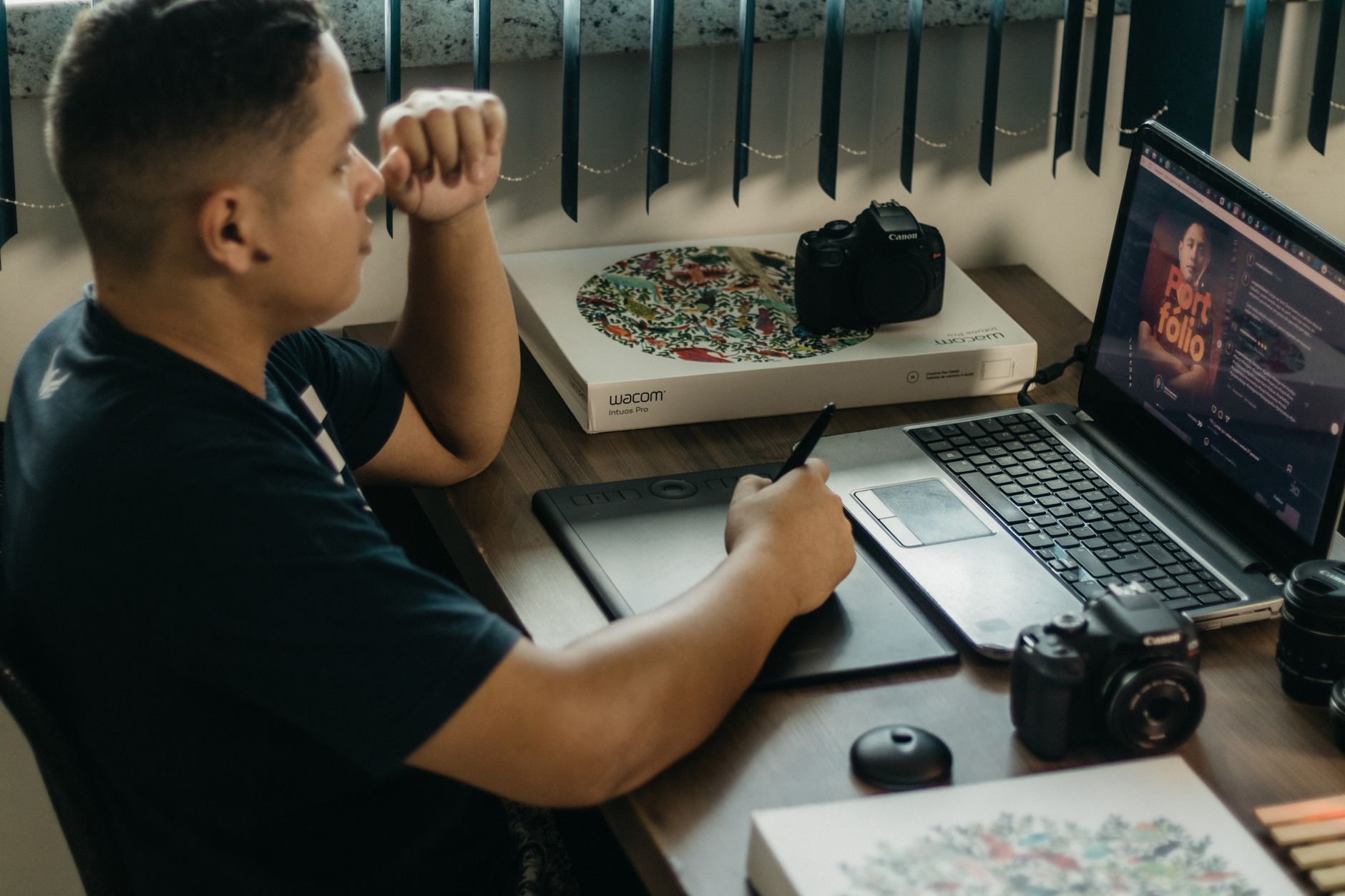 A person arranging colorful social media template layouts on a laptop screen in a bright home office