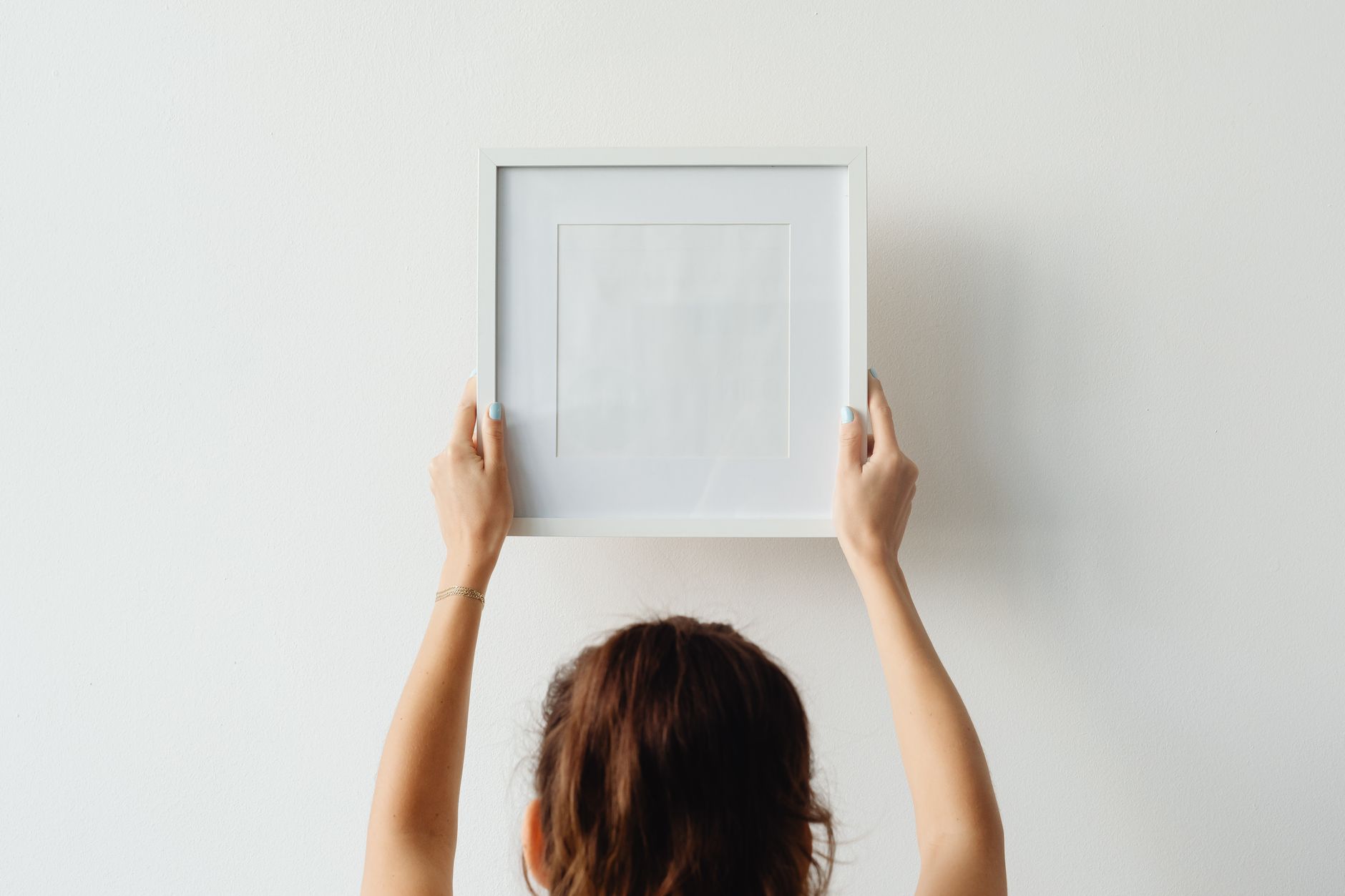 Three framed abstract art prints arranged on a plain white wall above a wooden bench