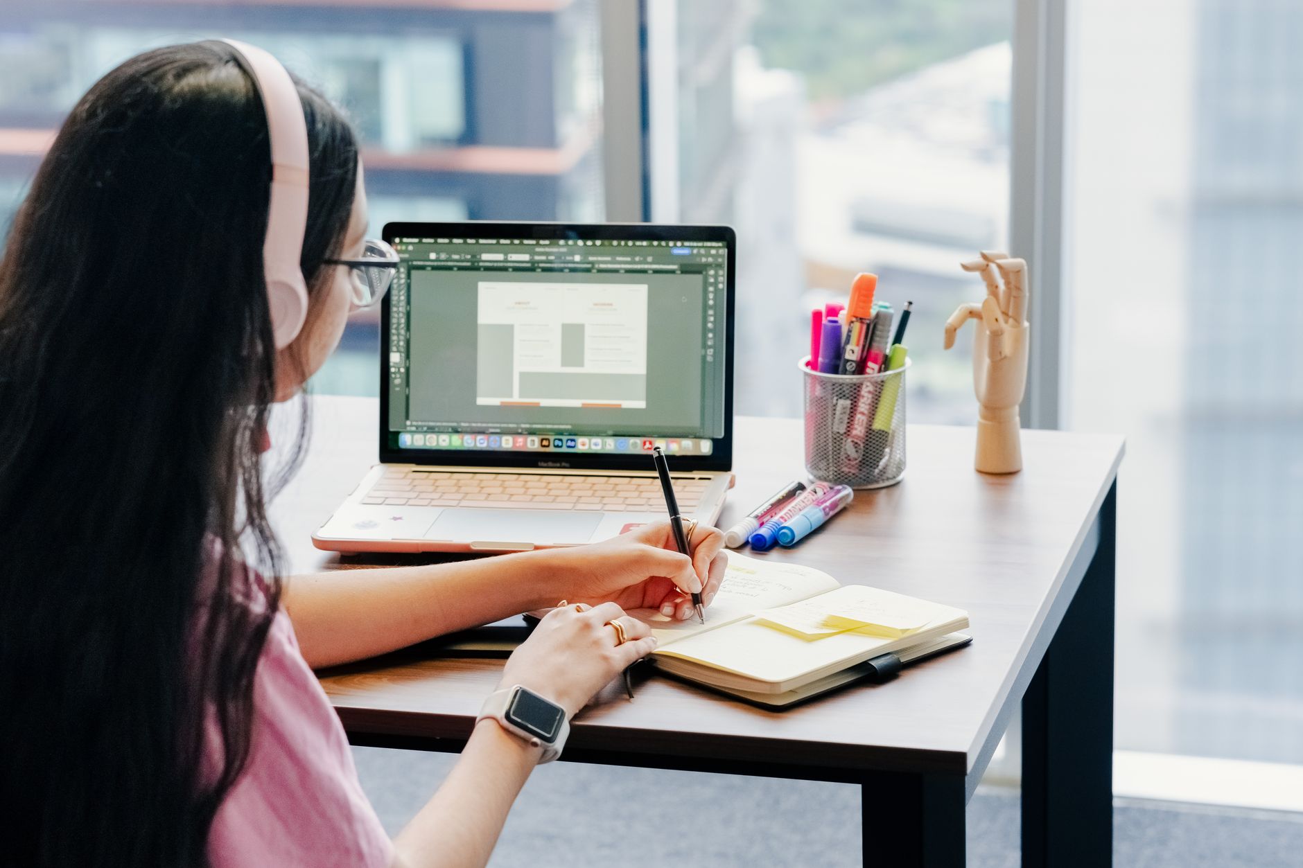 a woman designing a planner page on a laptop with a design tool open on screen