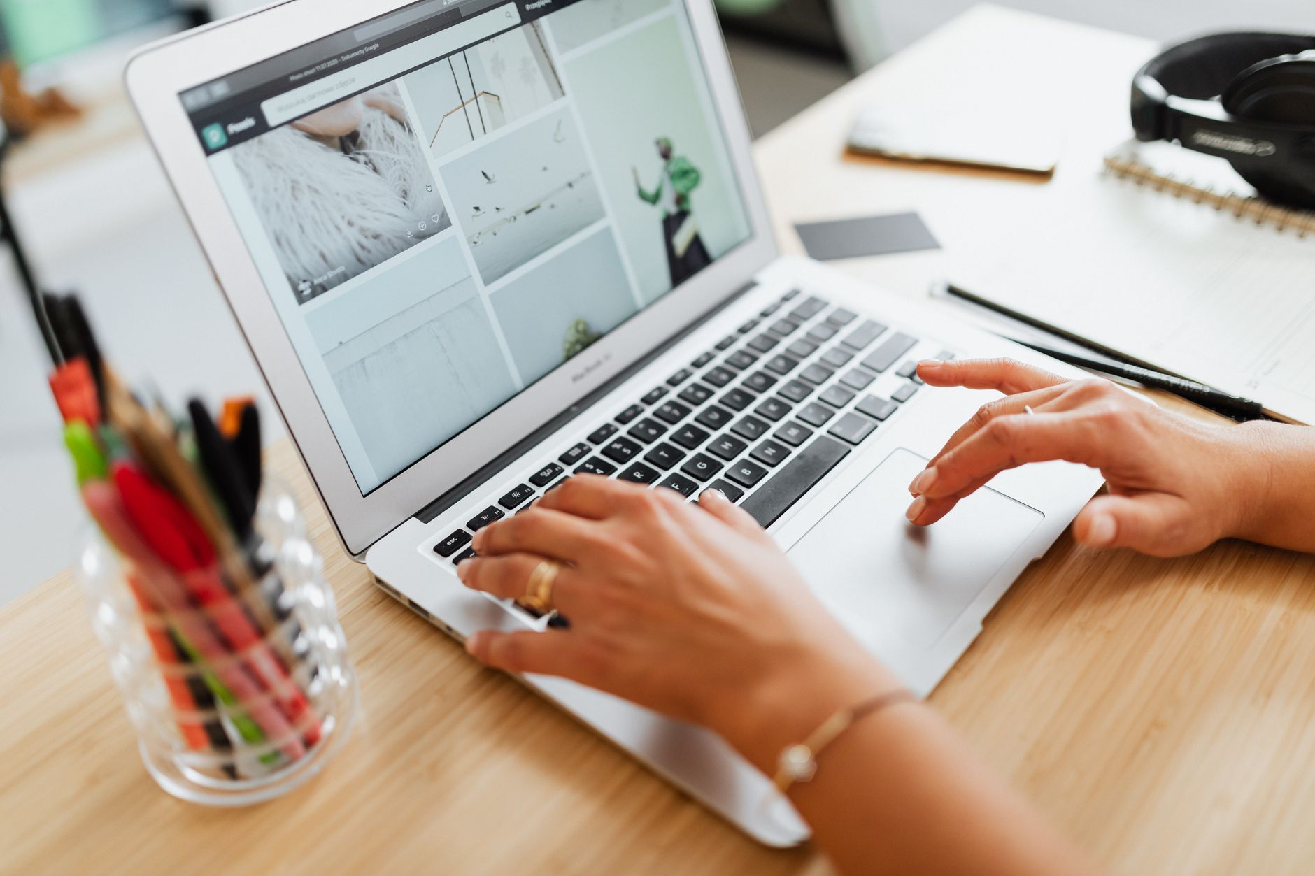 a person searching Etsy on a laptop while taking notes in a notebook