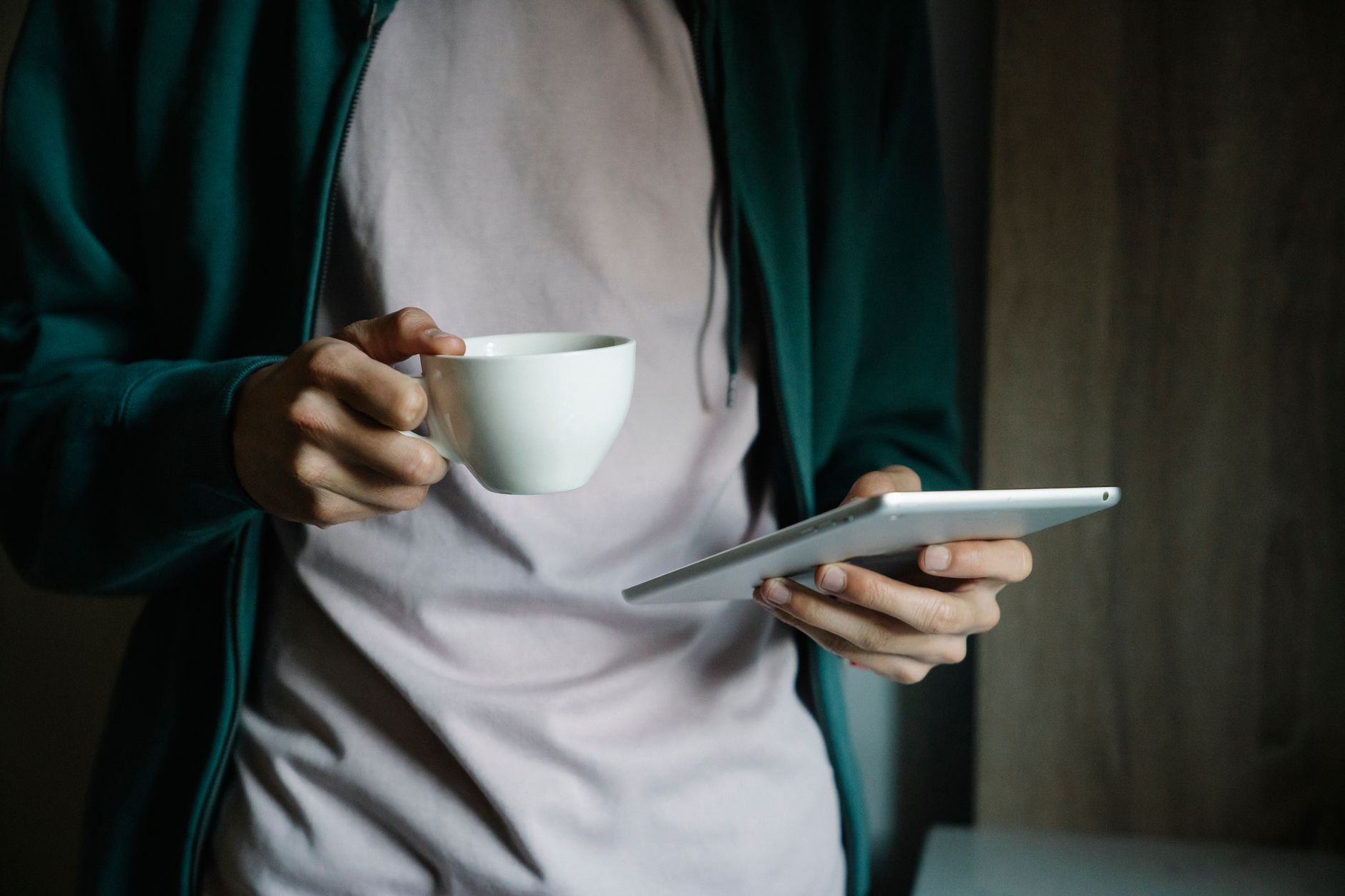 Person holding a tablet showing an ebook with a coffee cup on table