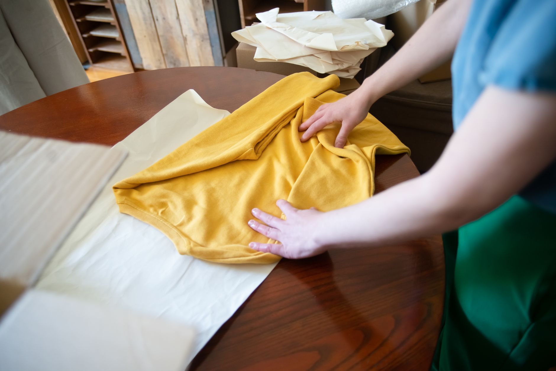 Stacked folded t-shirts on a wooden table in natural light