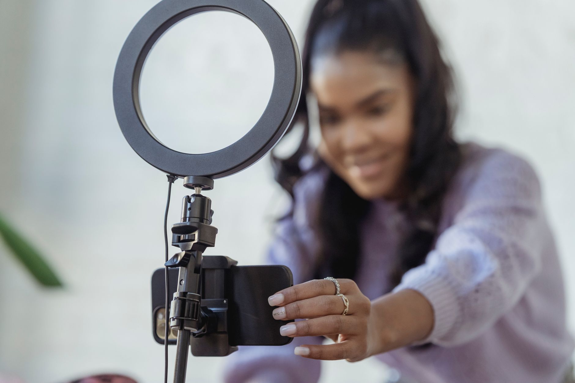 a person filming a vertical video with a smartphone on a tripod and ring light