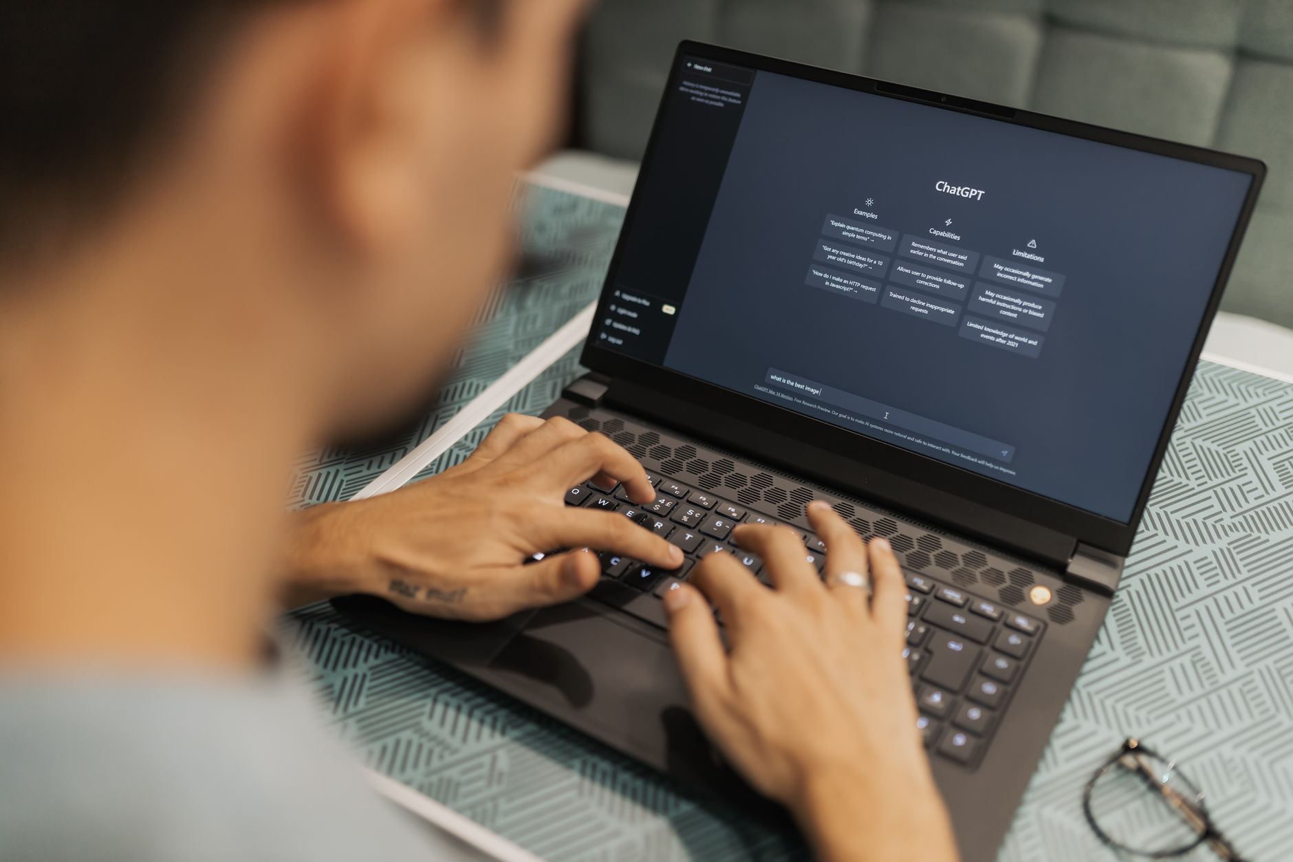 Person typing on laptop with AI chat interface on screen