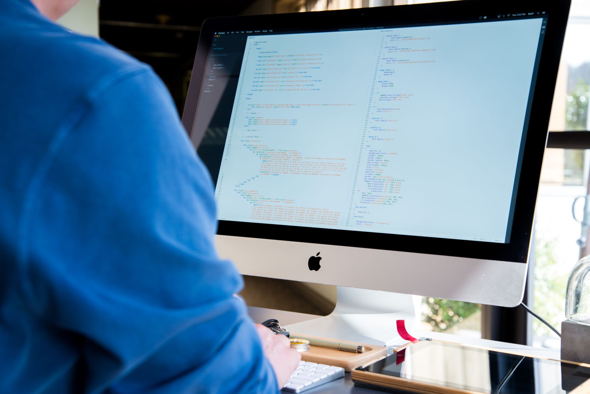 Software developer editing code on a large monitor in a workspace